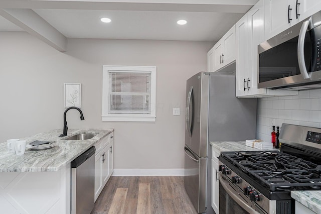 146 E Woodrow Ave, Columbus, OH 43207 - kitchen featuring appliances with stainless steel finishes, a sink, baseboards, backsplash, and wood finished floors