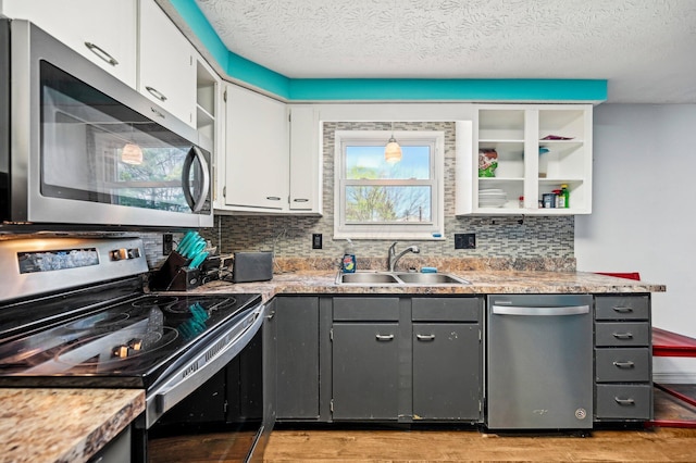 kitchen with light wood-type flooring, a sink, appliances with stainless steel finishes, and white cabinets
