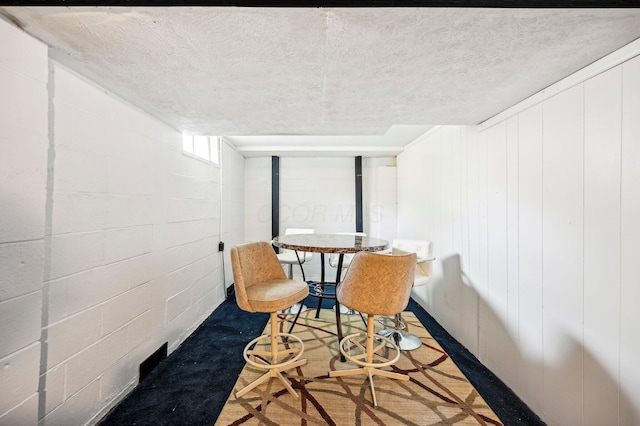 dining area with concrete block wall and a textured ceiling