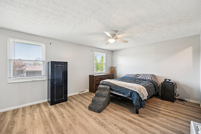 bedroom with visible vents, baseboards, a textured ceiling, a ceiling fan, and light wood finished floors