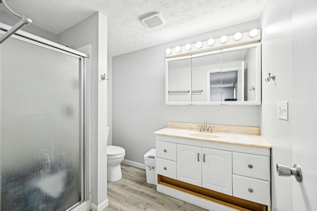 full bathroom featuring vanity, toilet, baseboards, wood finished floors, and a stall shower