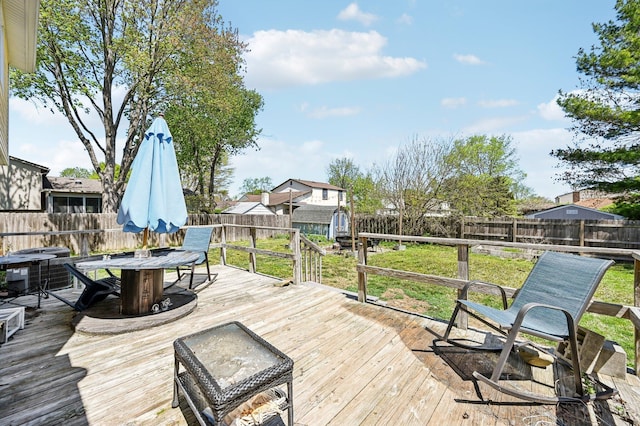 wooden deck with a fenced backyard, a storage unit, an outbuilding, and outdoor dining area
