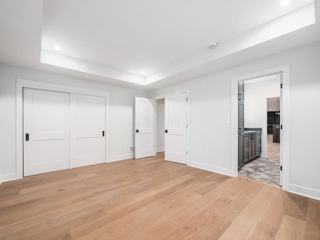 2355 Farleigh Rd, Columbus, OH 43221 - unfurnished bedroom featuring a tray ceiling, light wood-style floors, recessed lighting, baseboards, and connected bathroom