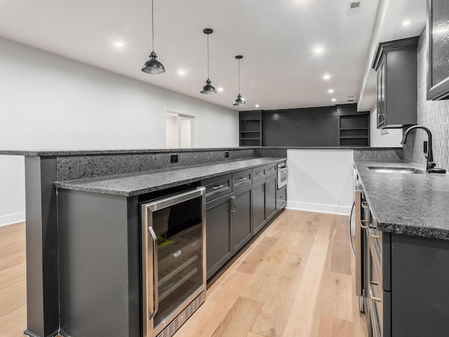 2355 Farleigh Rd, Columbus, OH 43221 - kitchen featuring beverage cooler, a sink, light wood-type flooring, dark stone counters, and hanging light fixtures