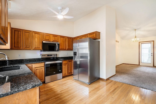 4977 Softwood Ct, Westerville, OH 43081 - kitchen with appliances with stainless steel finishes, a sink, brown cabinetry, ceiling fan, and high vaulted ceiling