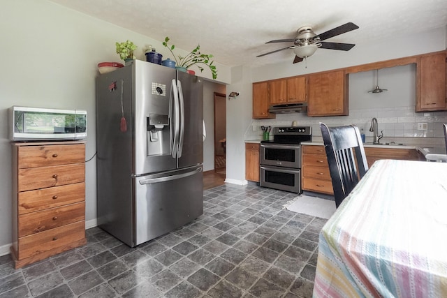 109 Williams Rd, Columbus, OH 43207 - kitchen featuring stainless steel appliances, under cabinet range hood, a sink, brown cabinets, and a ceiling fan