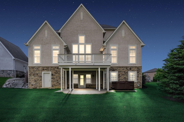 1393 Kearney Way, Delaware, OH 43015 - back of house at twilight with a hot tub, stone siding, stucco siding, a patio area, and a lawn