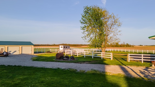 view of yard with a rural view, fence, an outbuilding, and a garage