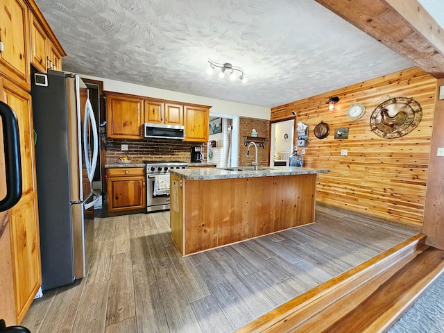 3851 Snow Hill Rd SW, Washington Court House, OH 43160 - kitchen featuring stainless steel appliances, light wood-style floors, a sink, wooden walls, and a center island with sink
