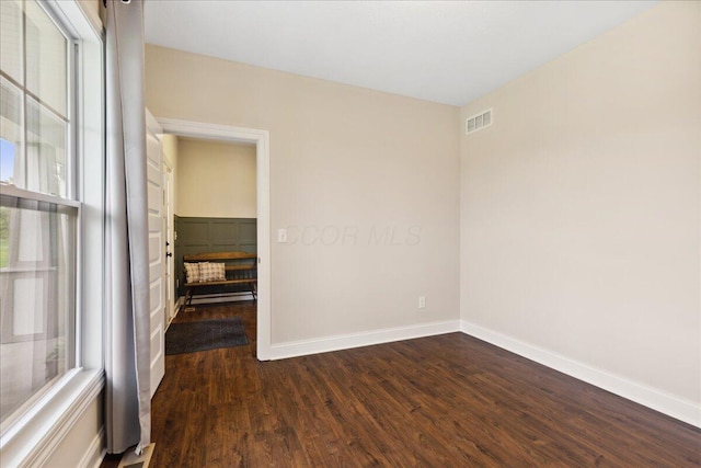 spare room with dark wood-type flooring and baseboards