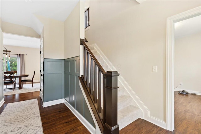 stairway with wood finished floors, baseboards, and vaulted ceiling