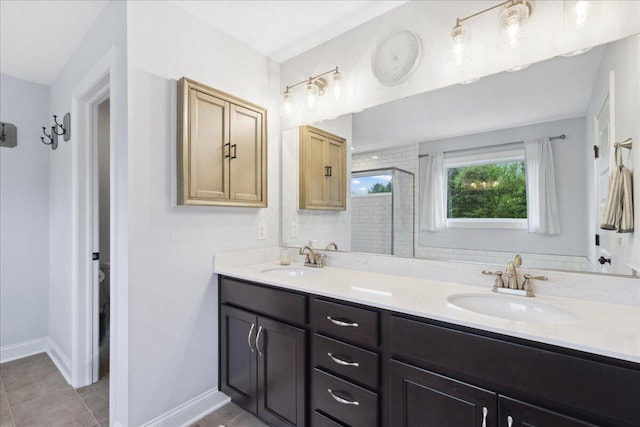 full bath with double vanity, tile patterned flooring, a shower stall, and baseboards