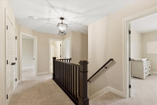 hall featuring an upstairs landing, light colored carpet, and baseboards