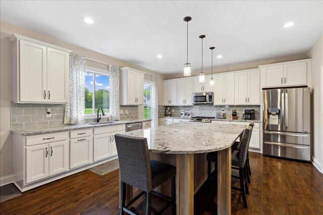 kitchen with stainless steel appliances, a sink, white cabinets, a kitchen breakfast bar, and recessed lighting