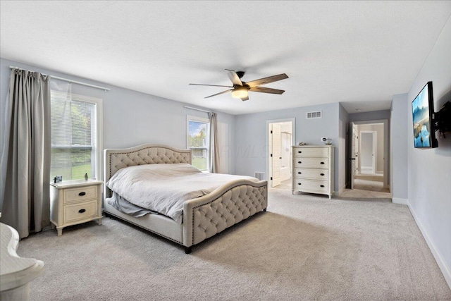 bedroom featuring light colored carpet, ceiling fan, baseboards, and connected bathroom