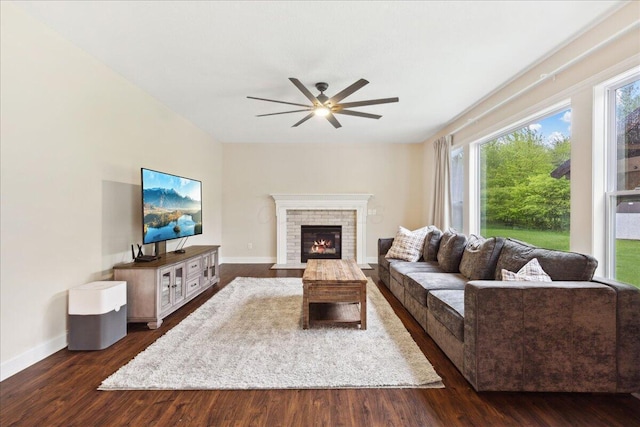living room featuring ceiling fan, a fireplace, dark wood-type flooring, and baseboards