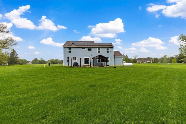 rear view of property featuring solar panels, a yard, and a gazebo