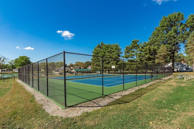 view of tennis court featuring fence and a yard