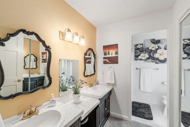 full bath with double vanity, toilet, baseboards, and a sink