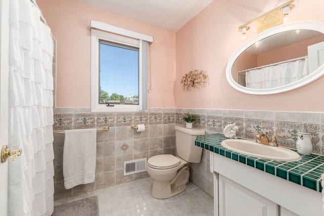 full bath with visible vents, tile walls, tile patterned floors, a wainscoted wall, and toilet