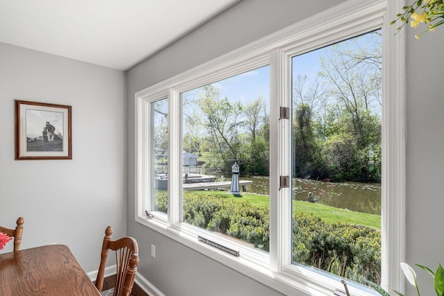interior space featuring baseboards, a water view, and a wealth of natural light