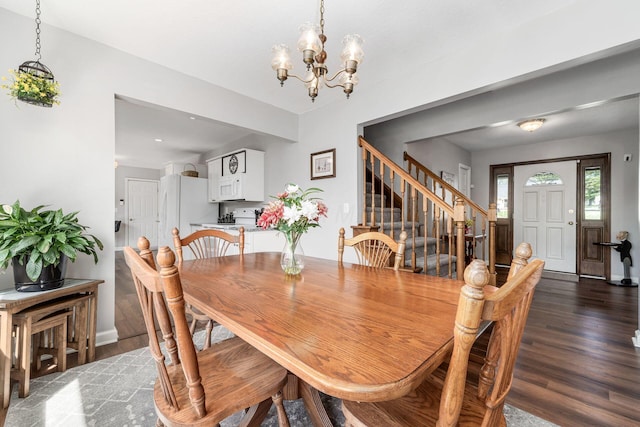 dining space featuring baseboards, a notable chandelier, wood finished floors, and stairway