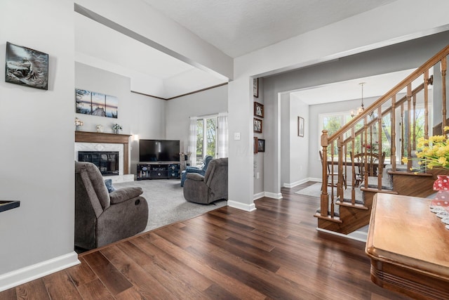 living area featuring stairway, baseboards, a high end fireplace, and dark wood-type flooring