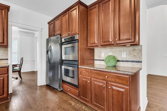 7169 Fernridge Dr, New Albany, OH 43054 - kitchen featuring stainless steel appliances, dark wood-type flooring, tasteful backsplash, and light stone counters