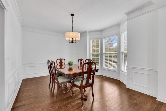 7169 Fernridge Dr, New Albany, OH 43054 - dining space with crown molding, a chandelier, a decorative wall, dark wood finished floors, and a wainscoted wall