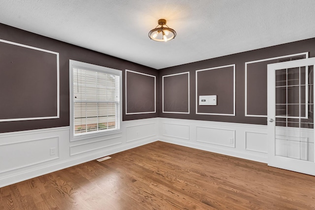 7169 Fernridge Dr, New Albany, OH 43054 - empty room featuring a decorative wall, wood finished floors, and wainscoting