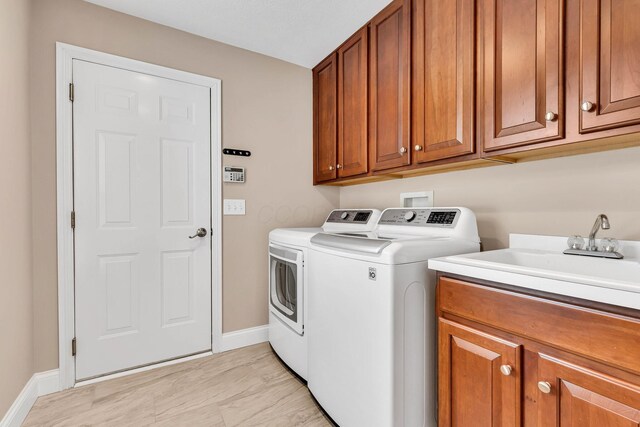 7169 Fernridge Dr, New Albany, OH 43054 - clothes washing area with independent washer and dryer, cabinet space, baseboards, and light wood-style flooring