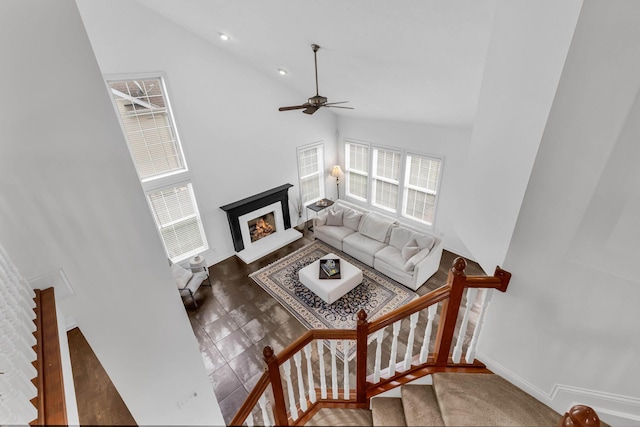 7169 Fernridge Dr, New Albany, OH 43054 - living area with high vaulted ceiling, a warm lit fireplace, ceiling fan, and stairs
