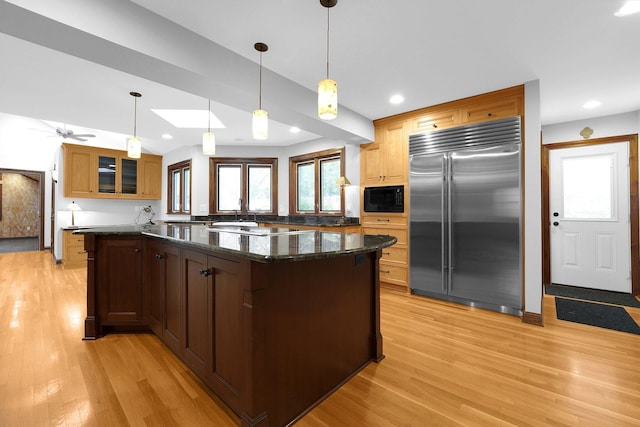 1799 Baldridge Rd, Columbus, OH 43221 - kitchen featuring built in appliances, light wood-type flooring, glass insert cabinets, a kitchen island, and dark stone countertops