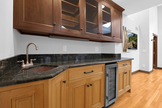 1799 Baldridge Rd, Columbus, OH 43221 - kitchen with wine cooler, a sink, light wood finished floors, glass insert cabinets, and dark stone counters