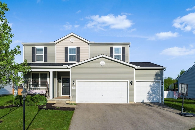 traditional home featuring asphalt driveway, a porch, a garage, and a front yard