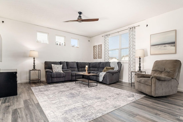living area with ceiling fan, healthy amount of natural light, wood finished floors, and baseboards