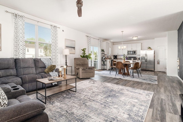 living room featuring a chandelier, wood finished floors, a ceiling fan, and baseboards