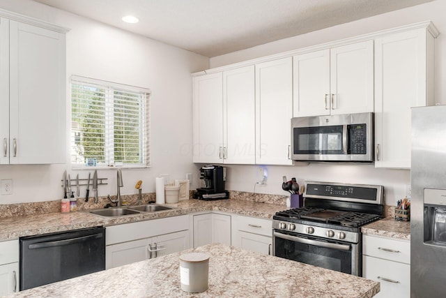 kitchen featuring stainless steel appliances, a sink, white cabinetry, recessed lighting, and light stone countertops