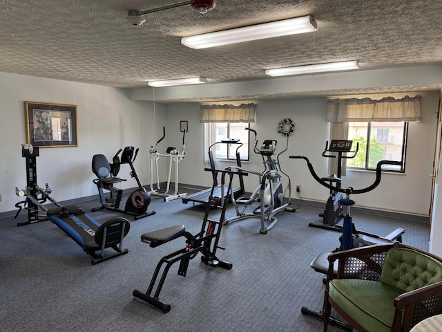 exercise room featuring a textured ceiling and baseboards
