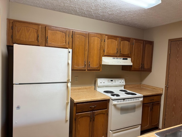kitchen with under cabinet range hood, white appliances, light countertops, and brown cabinets