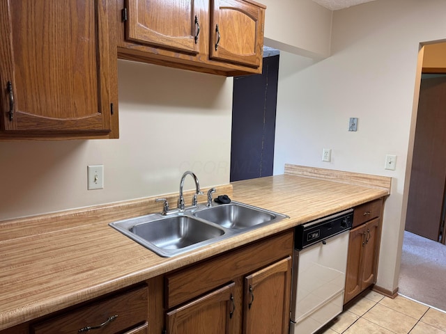 kitchen featuring dishwasher, light tile patterned flooring, a sink, brown cabinets, and light countertops