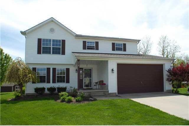 traditional home featuring a porch, driveway, a front lawn, and a garage