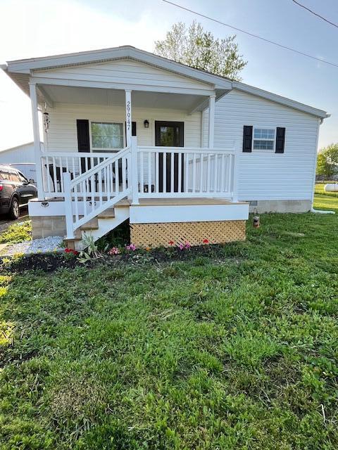 rear view of house with a porch and a yard