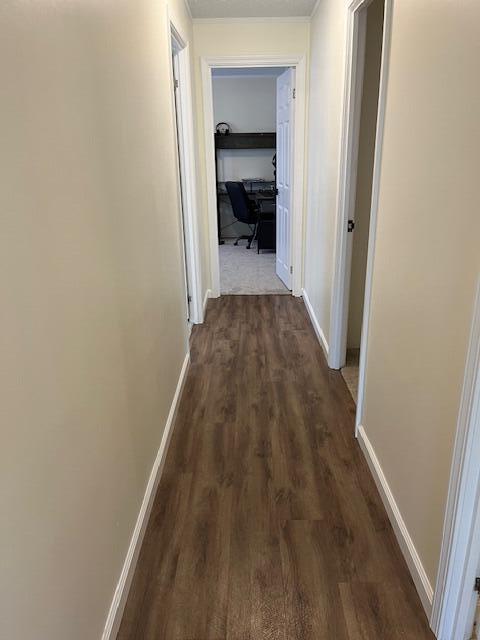 hall featuring baseboards and dark wood finished floors