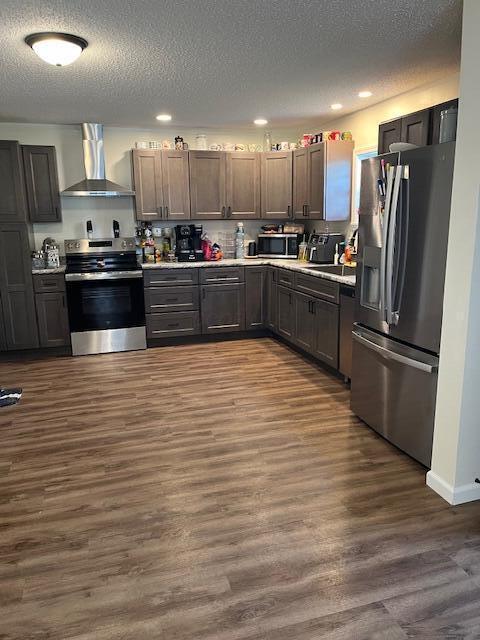 kitchen with stainless steel appliances, a textured ceiling, recessed lighting, and wall chimney exhaust hood