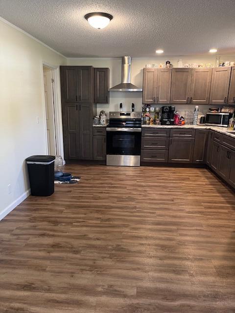 kitchen featuring wall chimney range hood, a textured ceiling, light countertops, dark wood-style floors, and appliances with stainless steel finishes