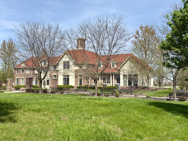 view of front of house featuring brick siding, a chimney, and a front lawn