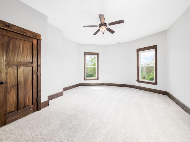 unfurnished bedroom featuring carpet floors, a ceiling fan, baseboards, and multiple windows