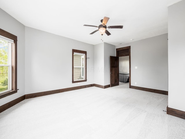 empty room with a ceiling fan, baseboards, and carpet