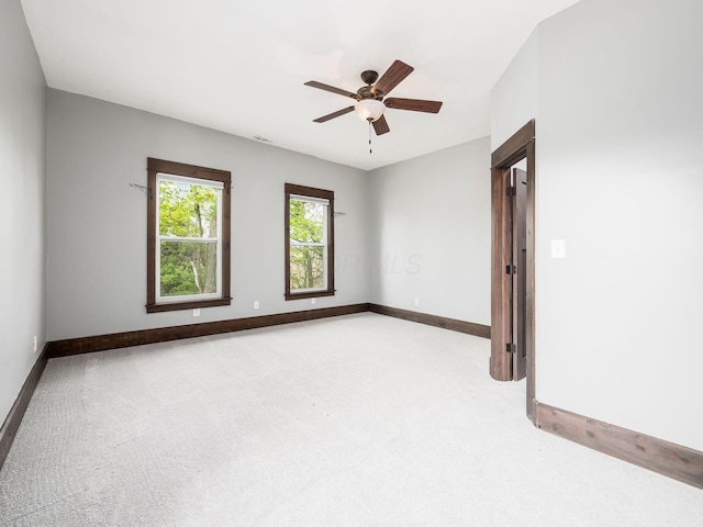 carpeted empty room featuring a ceiling fan and baseboards